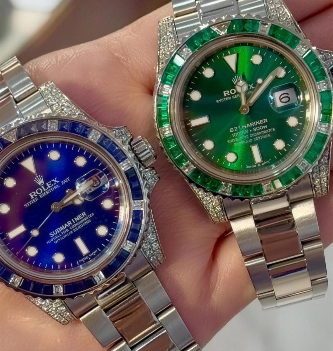Two Rolex Submariners with custom sapphire and emerald diamond bezels held in hand